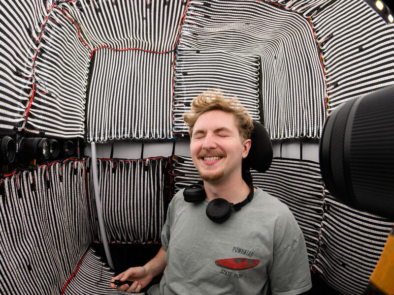A photo of a man sitting in a room covered in lights. 