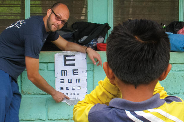 Zack Lipsman, M.D., checks the eyesight of a young boy during a 10-day service trip to Honduras as part of the HOMBRE program.