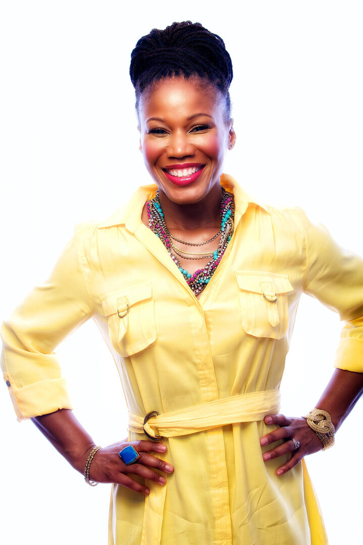 Smiling woman in yellow dress standing with hands on hips