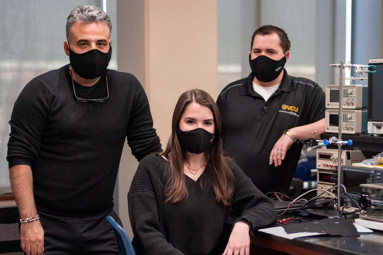 Three people in a laboratory wearing facial masks.