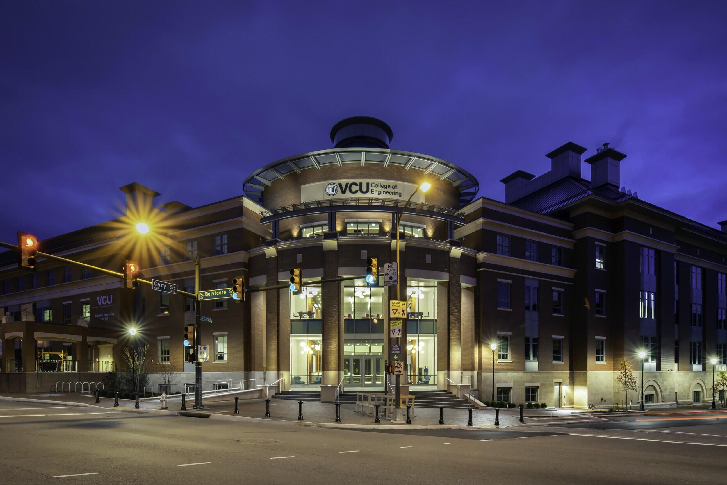 An exterior photo of a VCU College of Engineering building lit up at night.