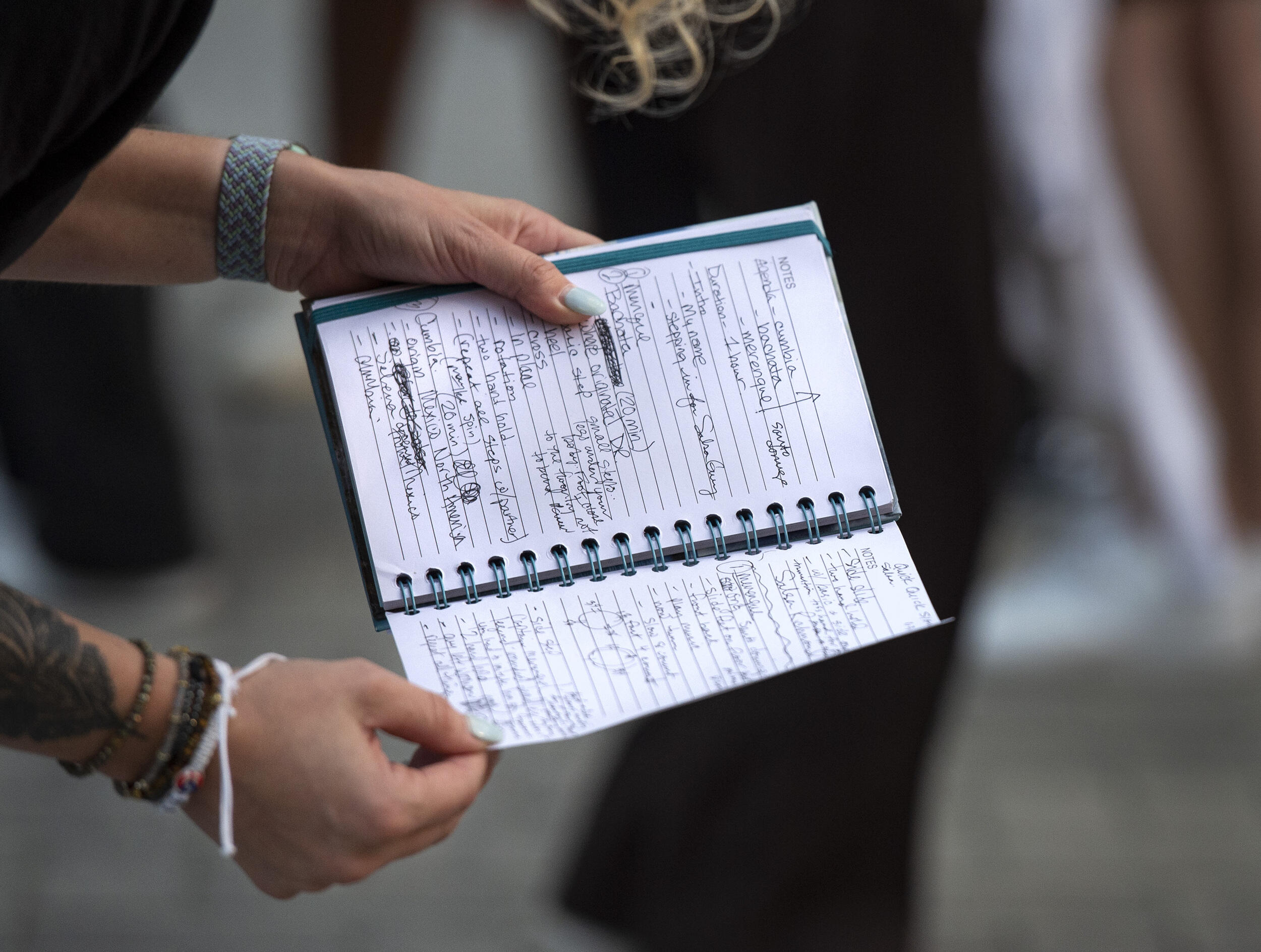 Two hands holding a notebook with writing in it