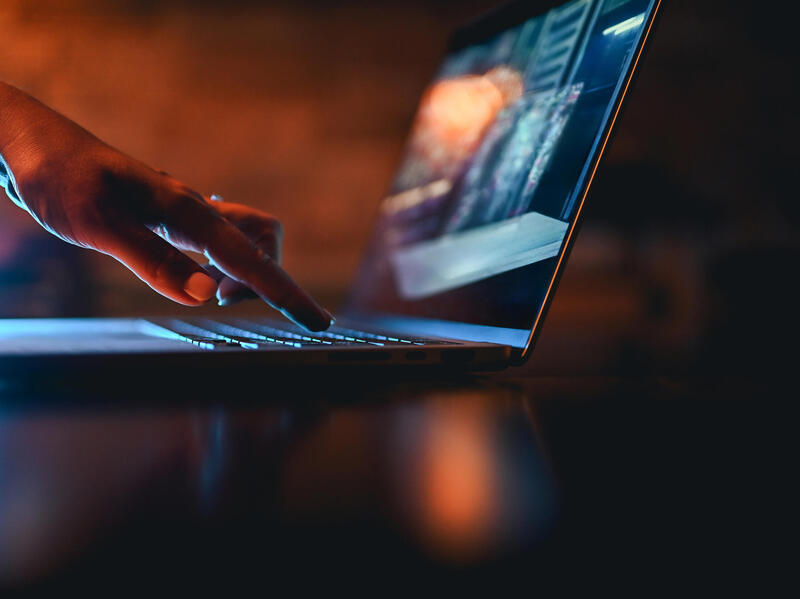 A photo of a hand pressing one key on a laptop. 