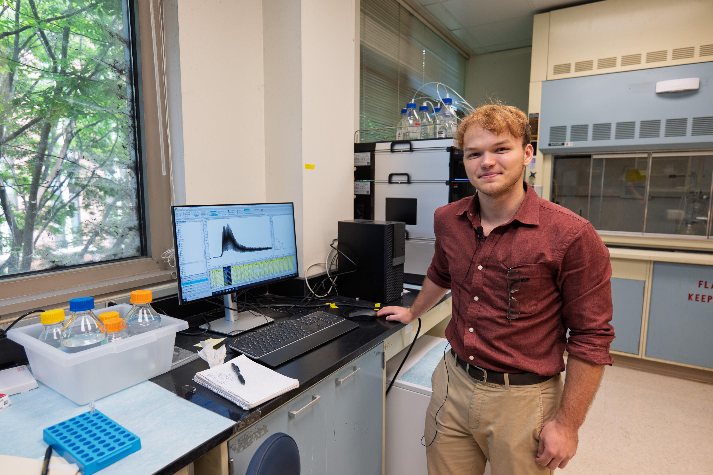 A man stands in a lab setting near a computer screen.