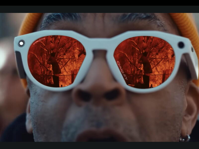 A close up photo of a man wearing white sunglasses. 