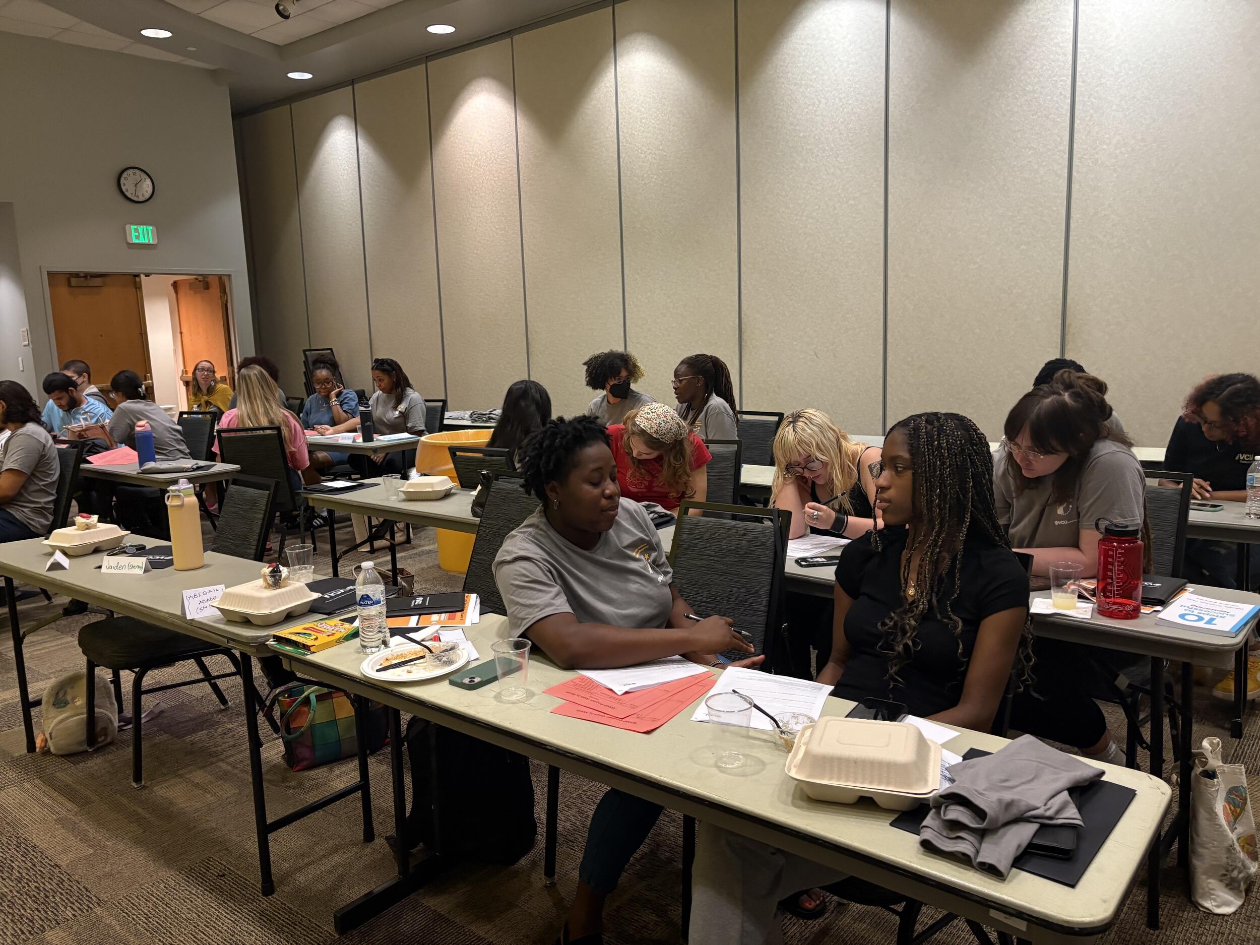 A photo of groups of people talking to each other in a classroom. 