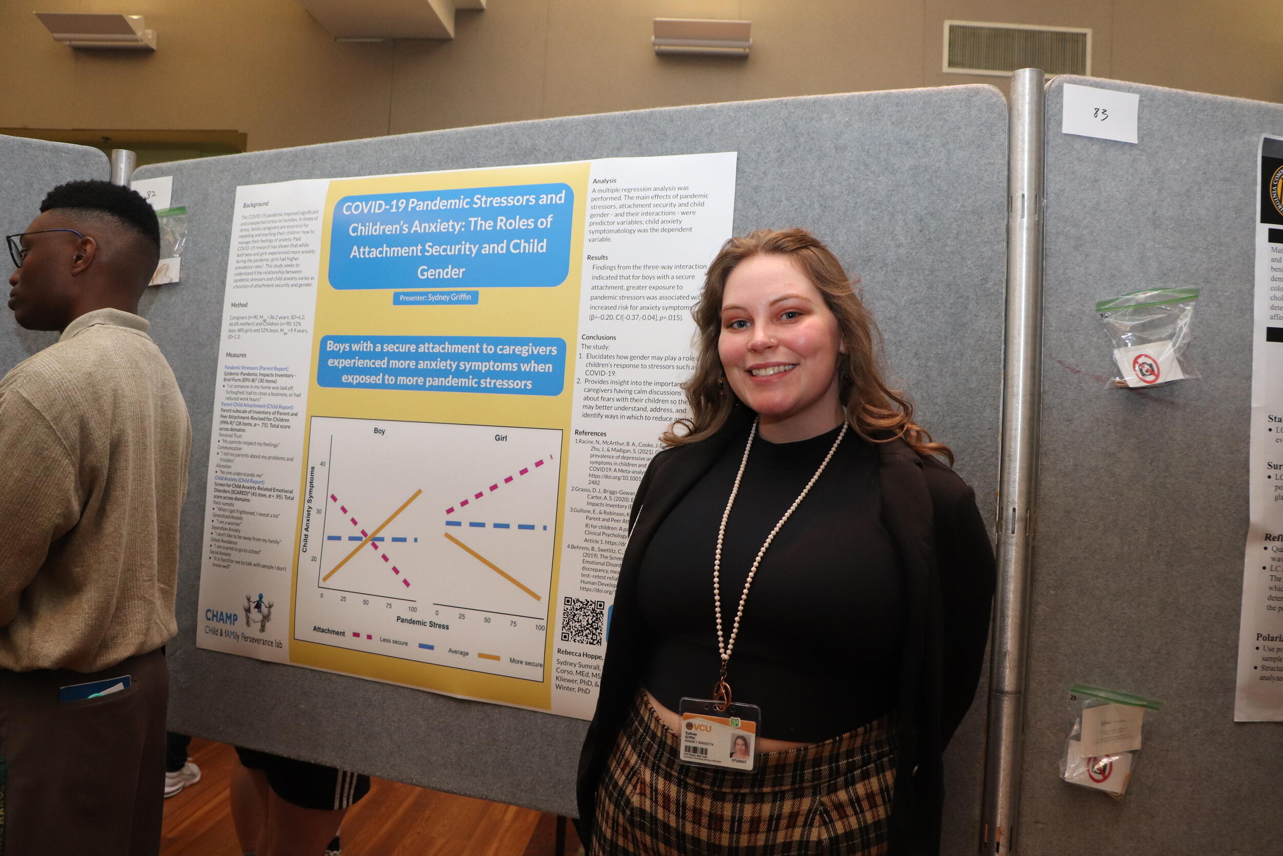 A photo of a woman standing to the right of a poster with research findings on it. 