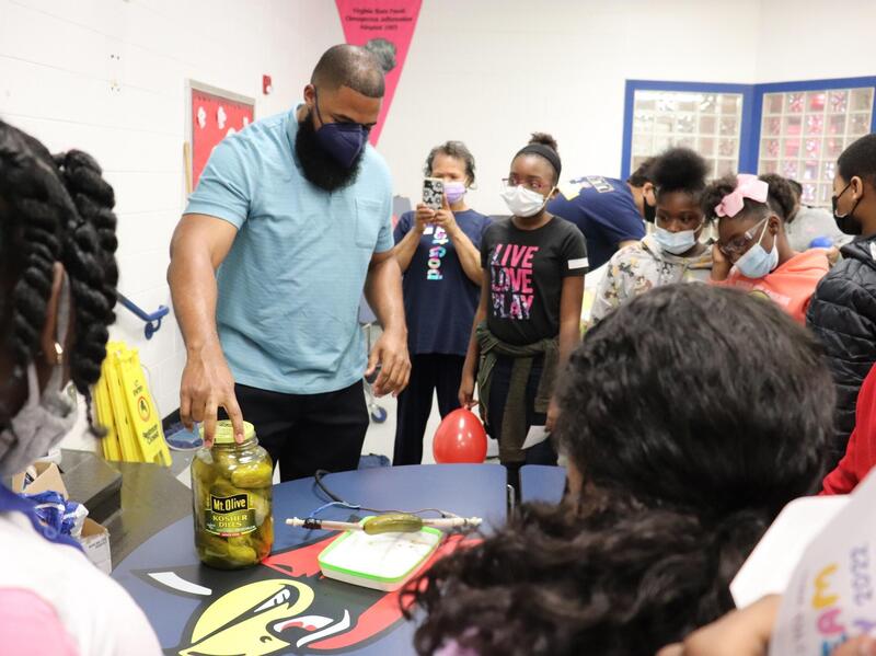 At STEAM Day, Mychal Smith, Ph.D., an assistant professor of chemistry at VCU, turns a pickle into a battery for fifth-graders at Patrick Copeland Elementary School in Hopewell. VCU students and faculty volunteered on the first day of spring break to teach grade-school students about science, technology, engineering, the arts and math. (Alexis Finc, VCU College of Humanities and Sciences)