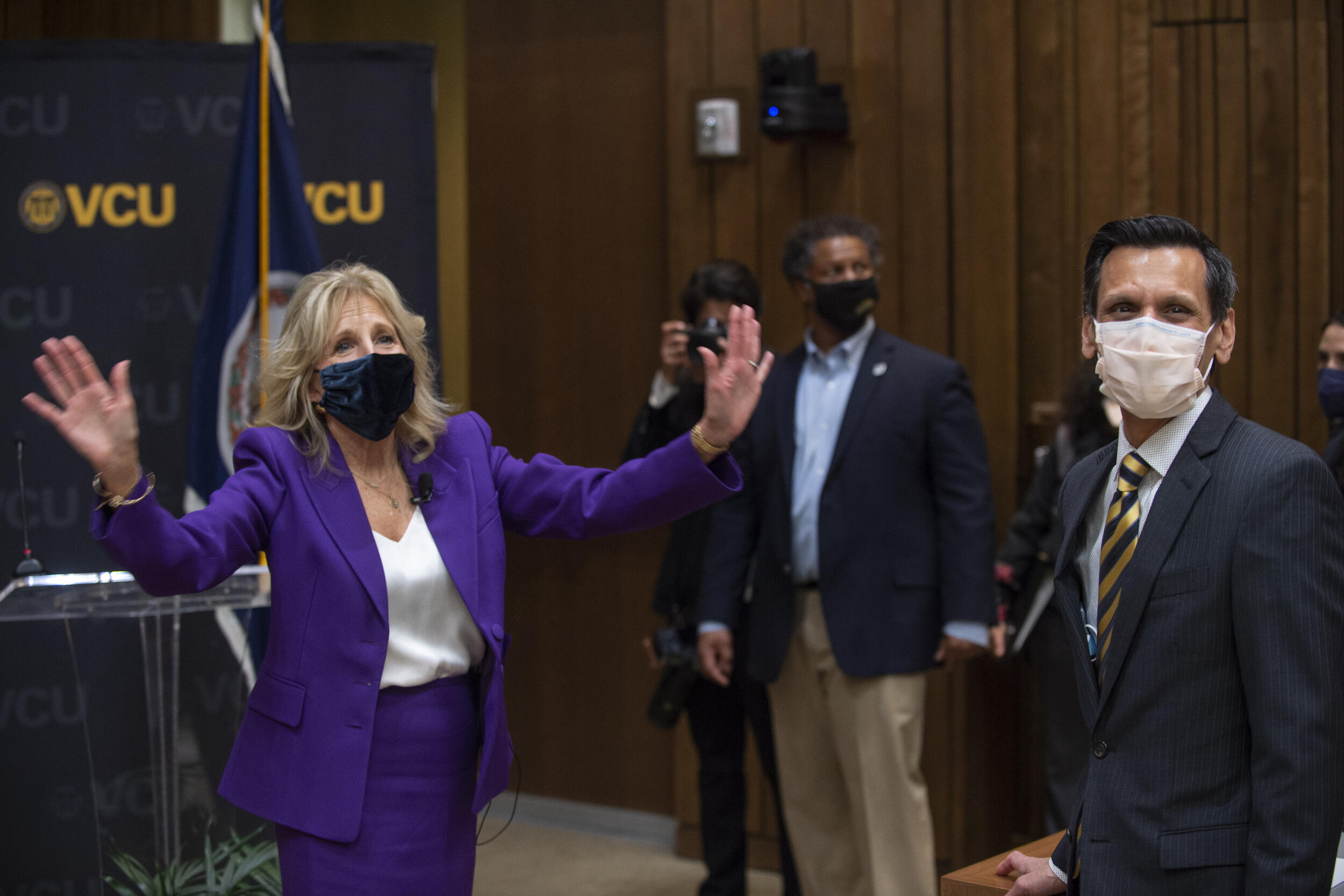 First lady Jill Biden, Ed.D., bids farewell to the audience. At right is VCU President Michael Rao, Ph.D. In the background (center) is Robert Winn, M.D., director of Massey Cancer Center.