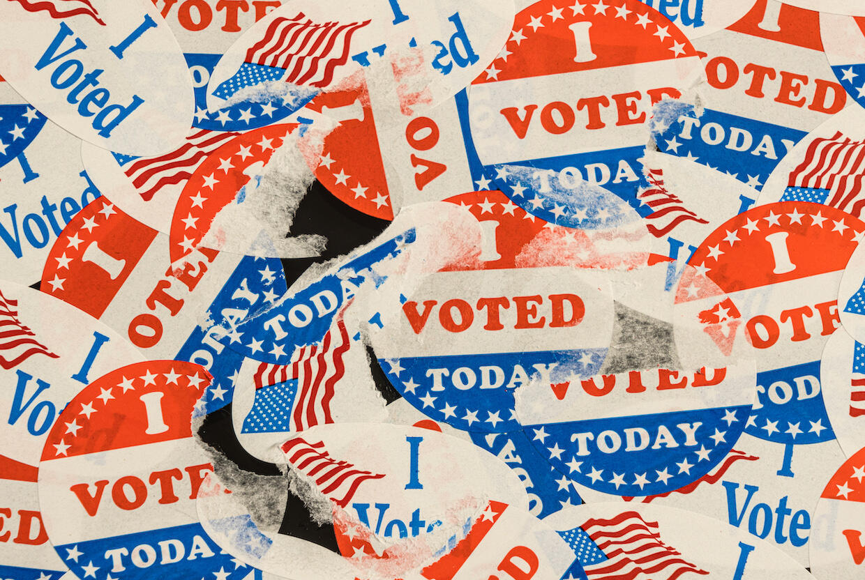 A photo of dozens of \"I voted today\" stickers stacked on top of each other. Some have been ripped and are only partially showing. 
