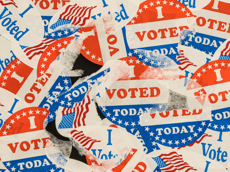A photo of dozens of \"I voted today\" stickers stacked on top of each other. Some have been ripped and are only partially showing. 