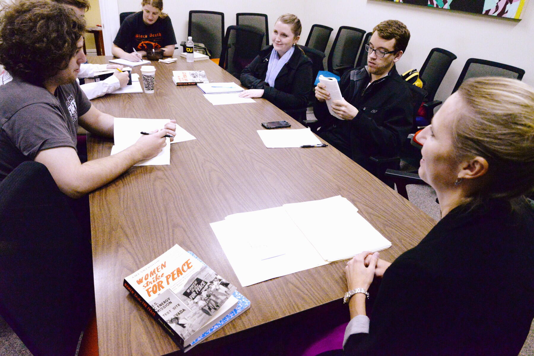 A group of people with books and notebooks seated around a table.