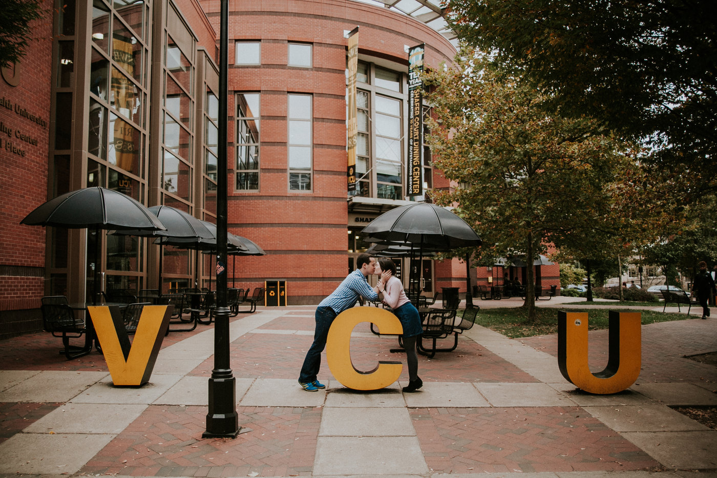 Two people kissing over large V C U letters.