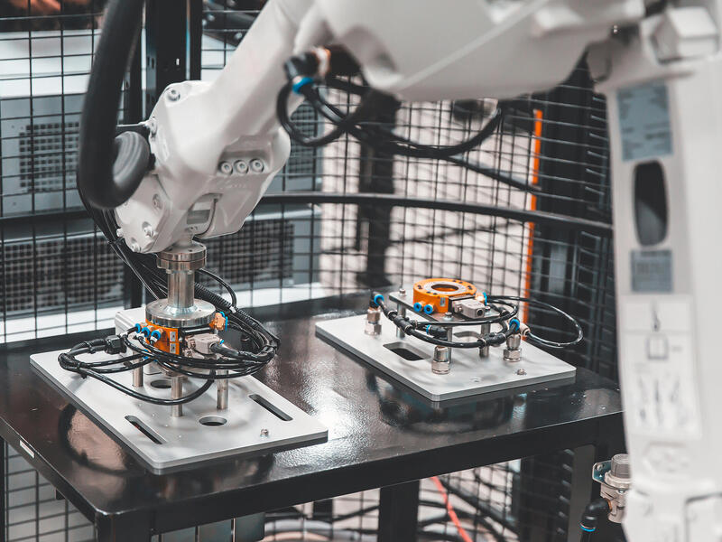 A photo of a robotic arm working on electronics. 