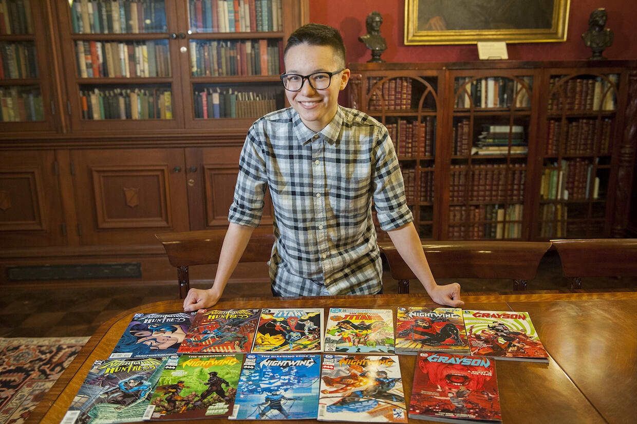 Thea Cheuk standing at a table with comic books spread out in front.