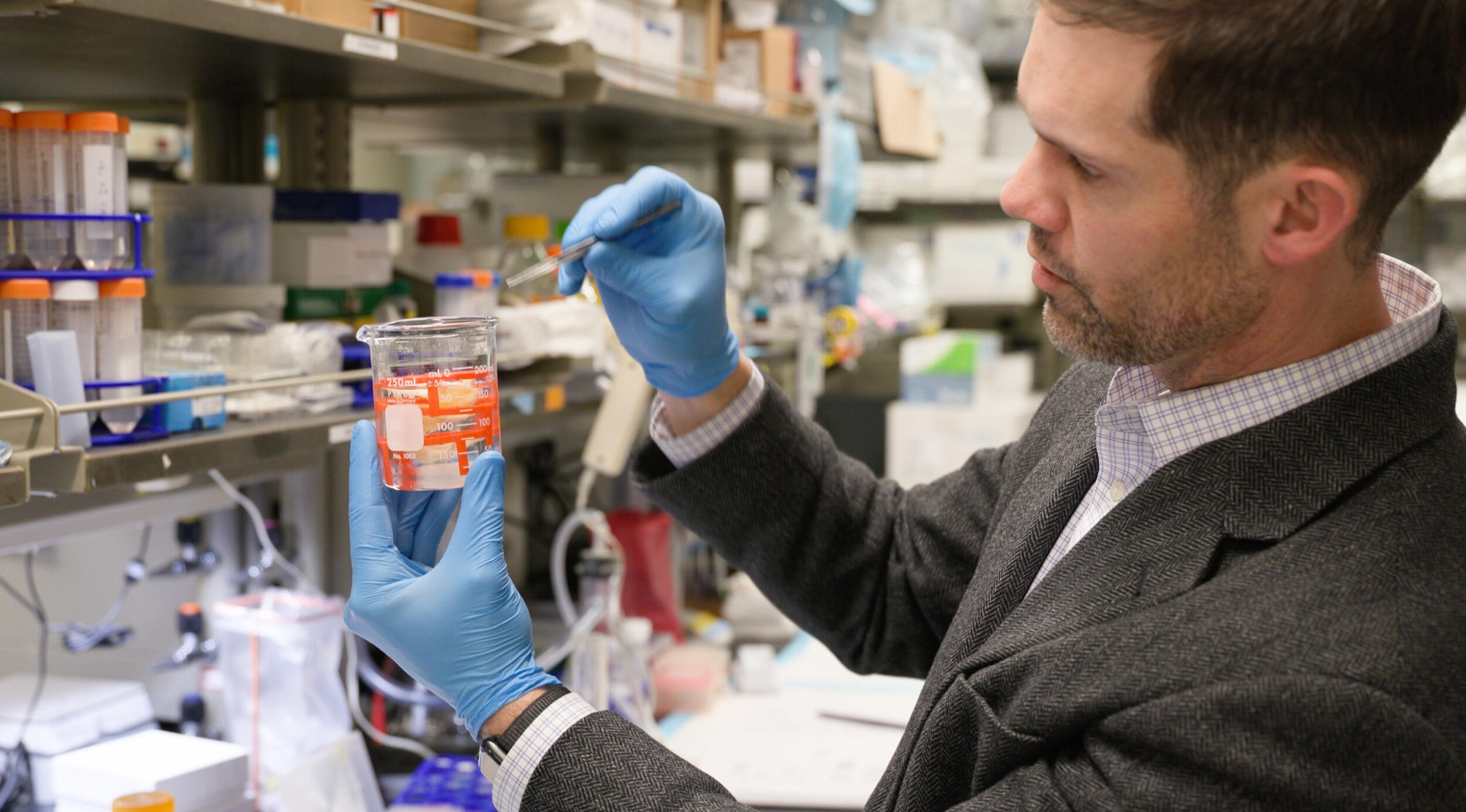 A man wearing blue gloves works in a lab.