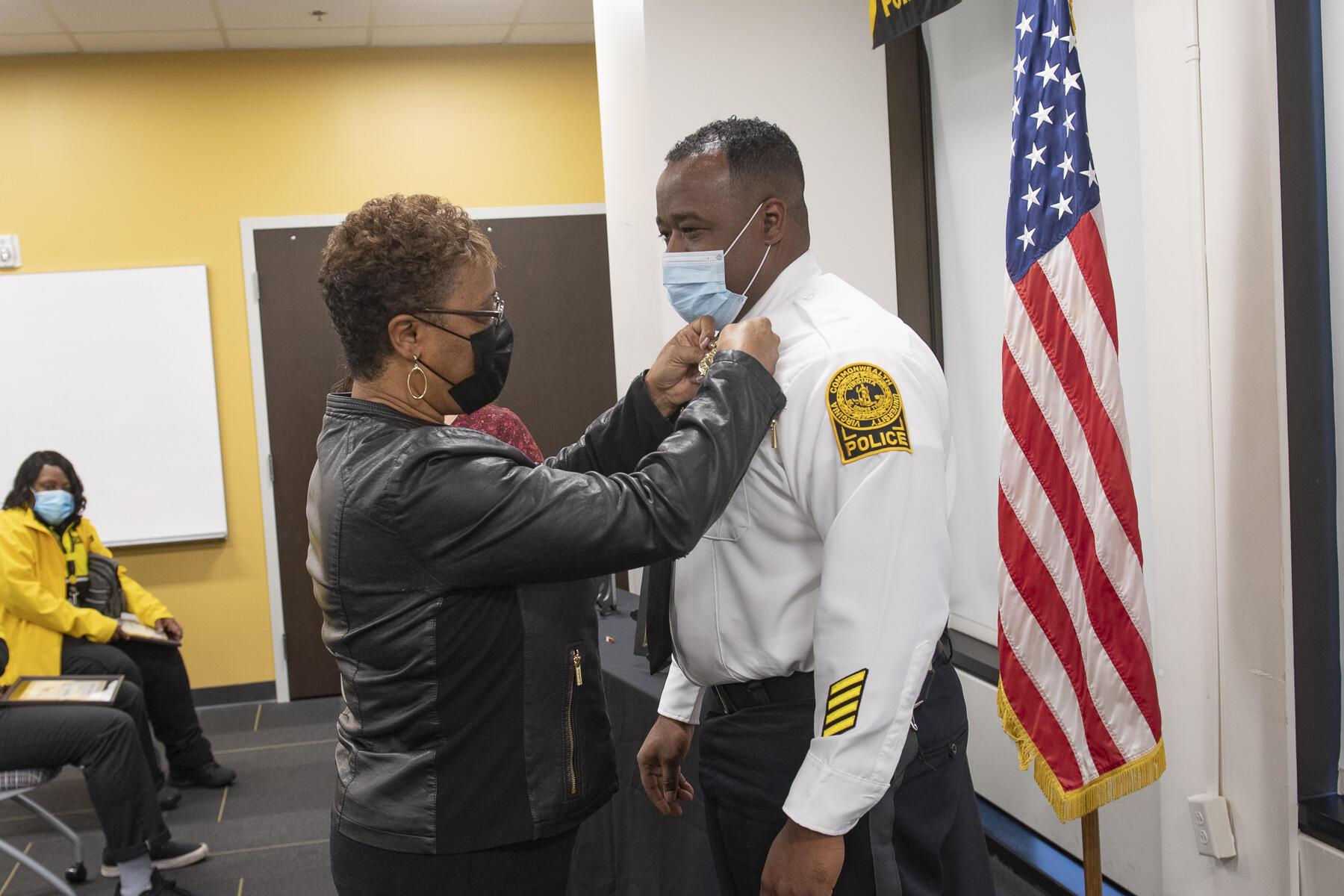 As part of the ceremony marking his promotion to assistant chief of police, Ervin Taylor, right, receives an \"assistant chief\" badge on his uniform, pinned by his mother