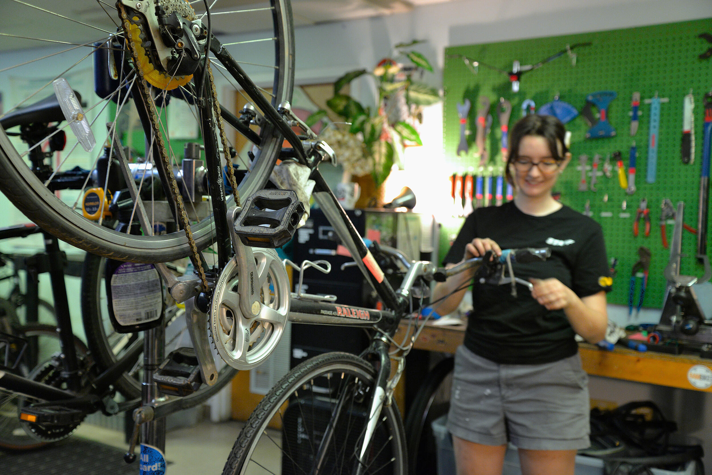 A photo of a person holding a tool behind a bicycle.