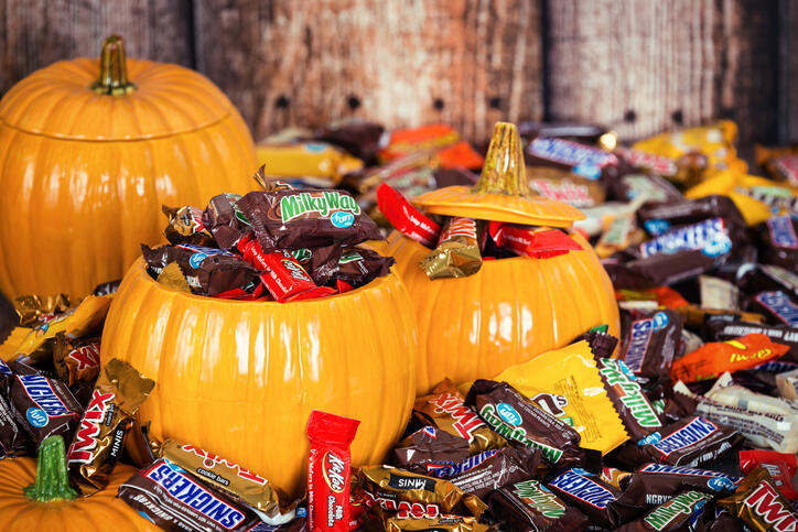A photo of fake pumpkins filled with pieces of chocolate candy.
