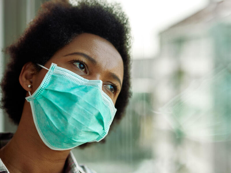 Person with mask looking out window. 