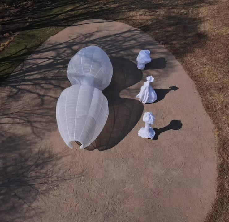 A white structure is viewed from above alongside three smaller structures.