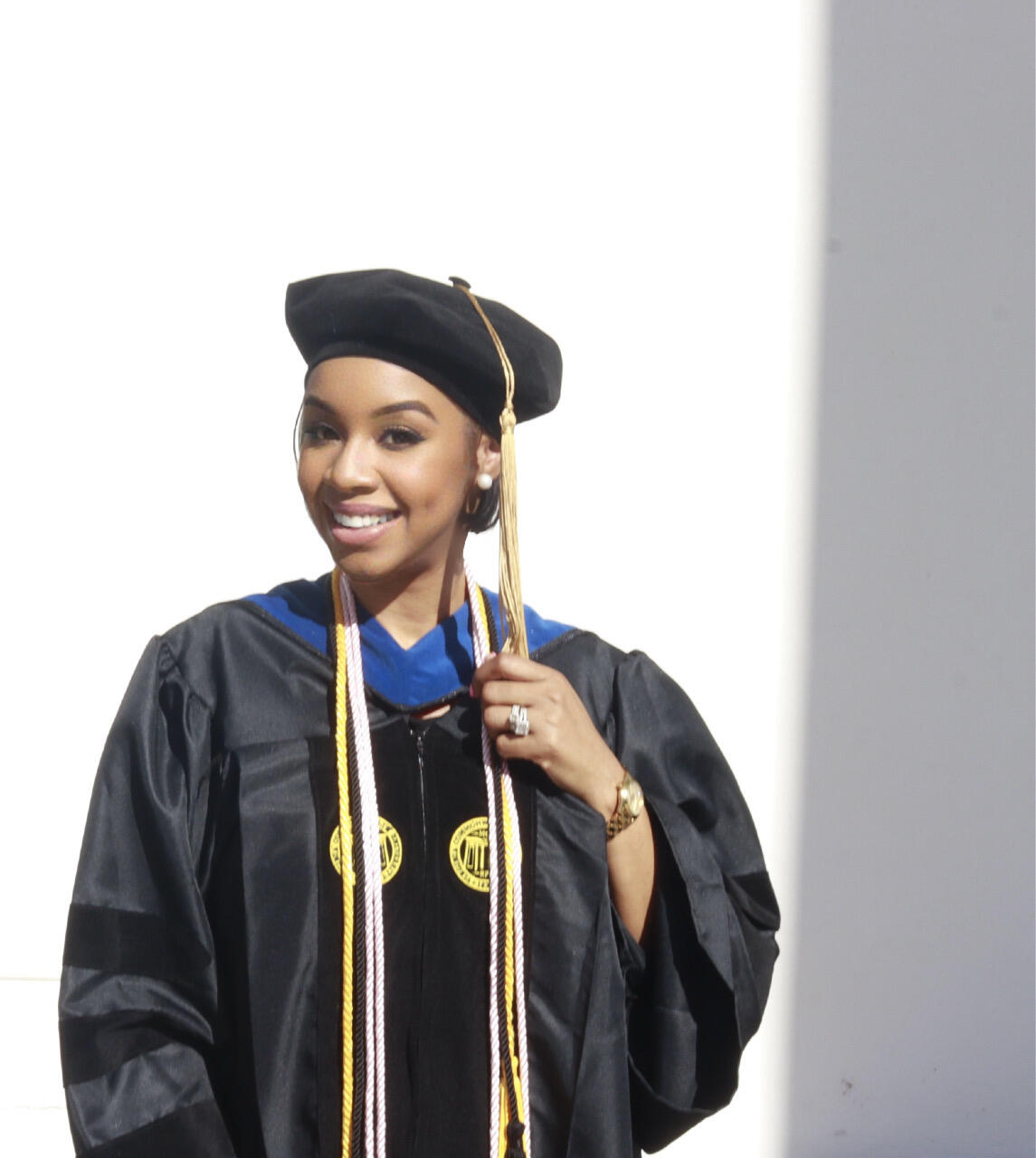 A photo of a woman from the chest up wearing a doctoral graduation cap and gown. 