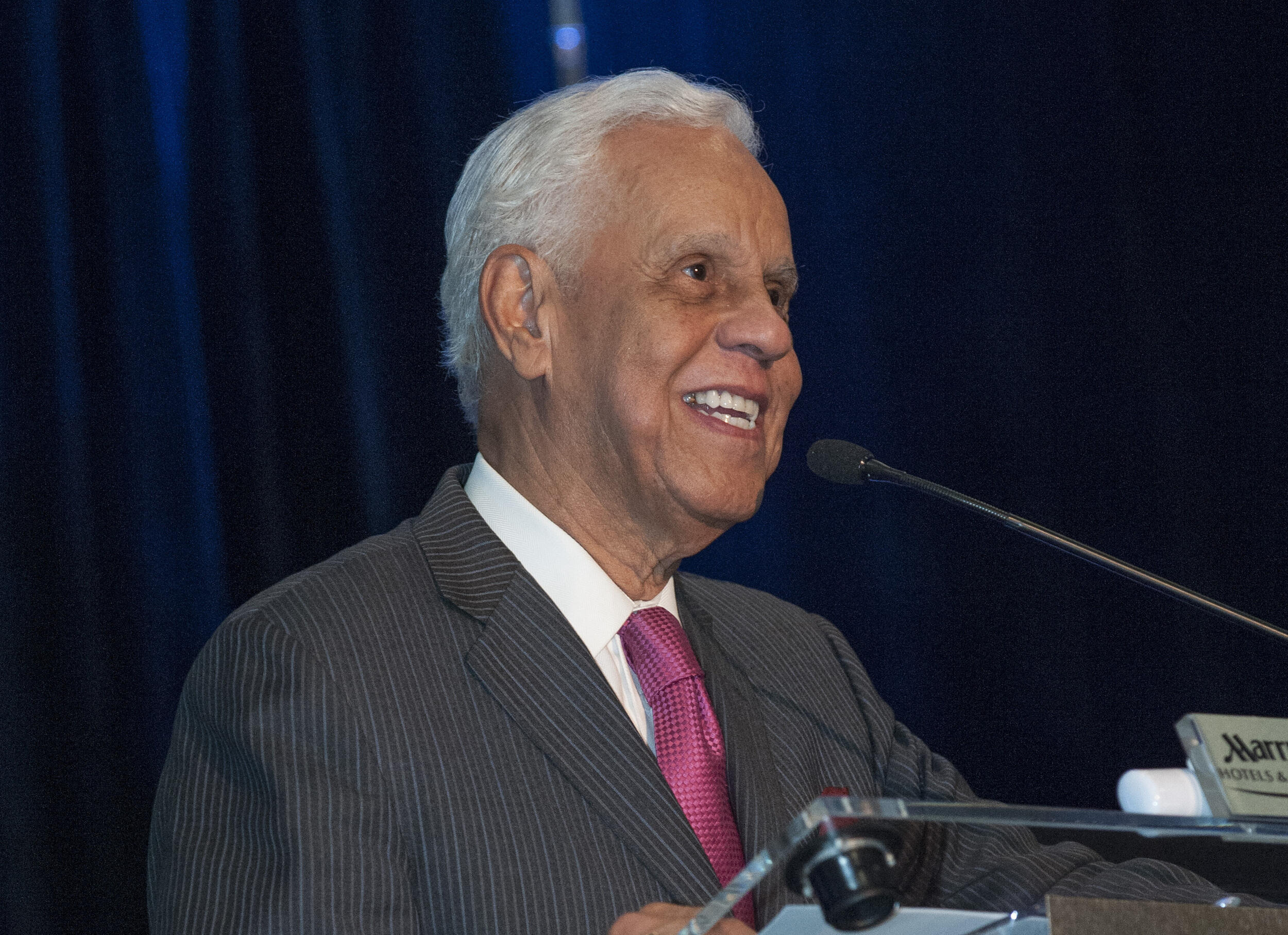 L. Douglas Wilder standing at a podium speaking into a microphone 