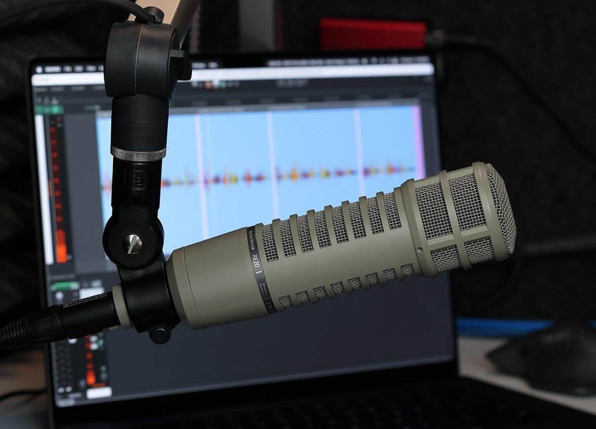 A recording microphone in front of a computer with audio levels on the screen. 