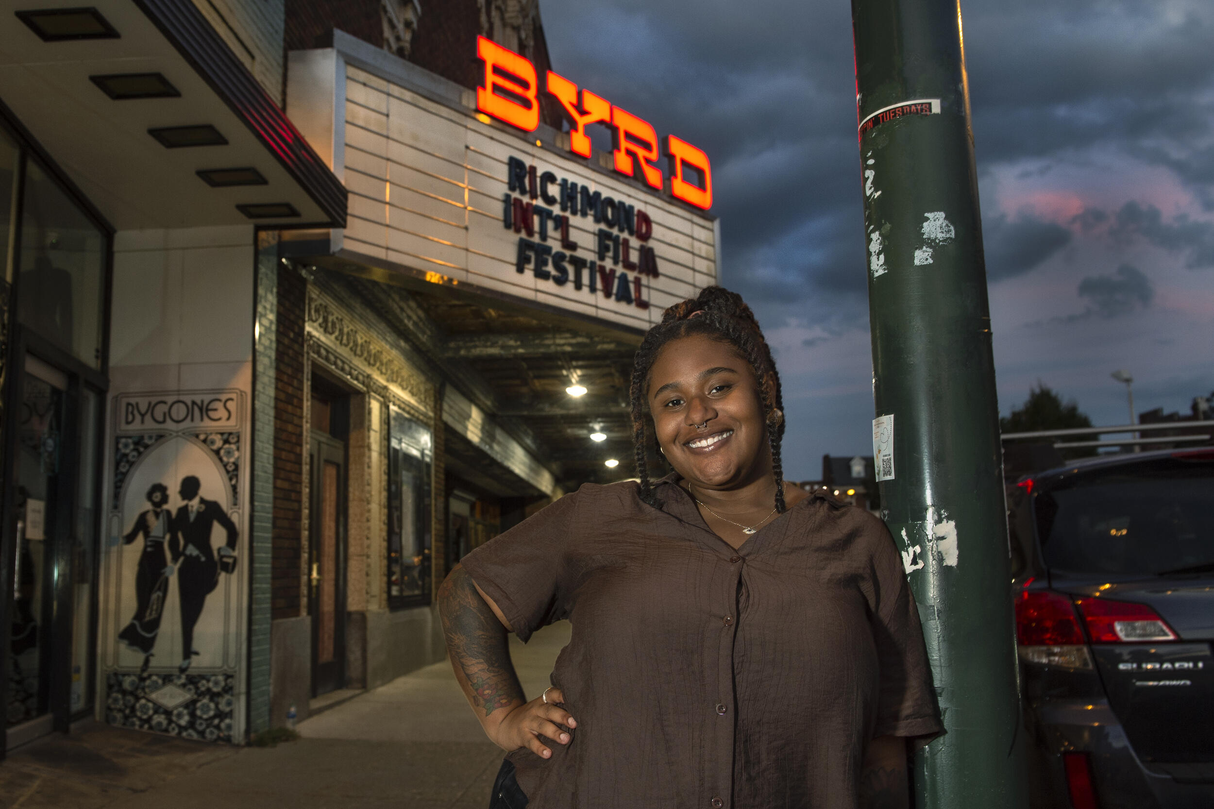 A photo of a woman standing in front of the Byrd Theater with her left hand on her hip. 