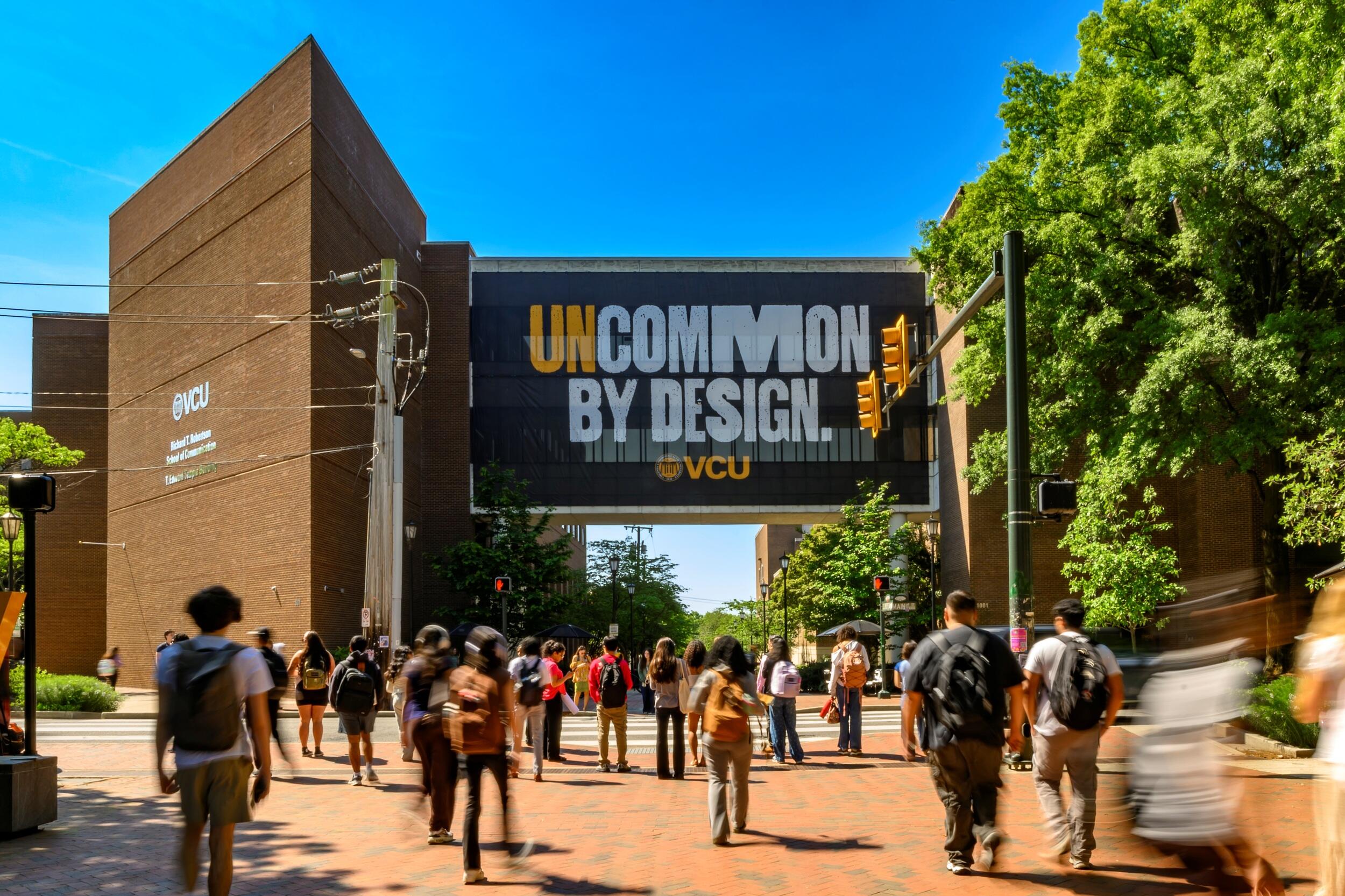 Students down a path toward a sign that reads \"Uncommon By Design\"