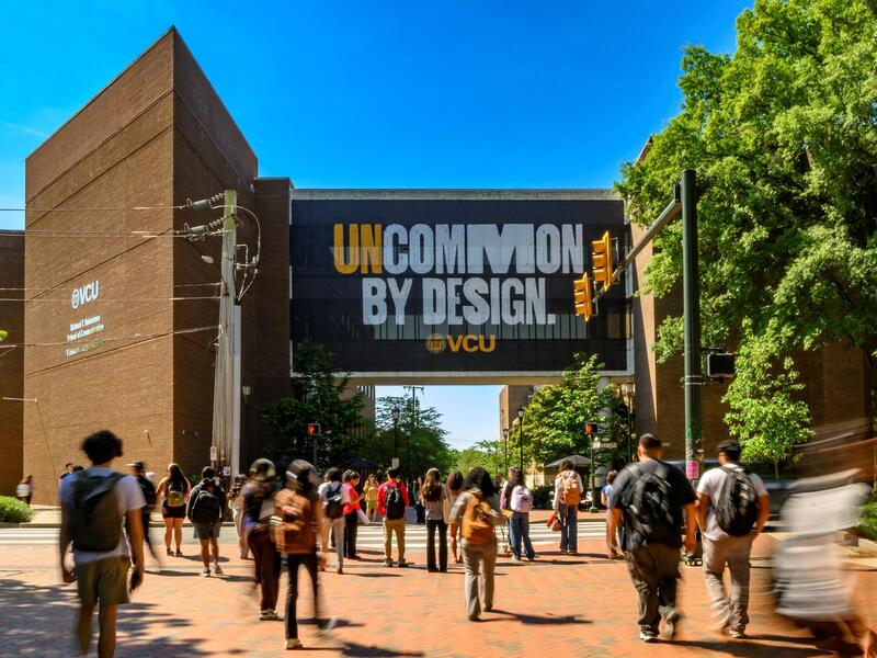 Students down a path toward a sign that reads \"Uncommon By Design\"