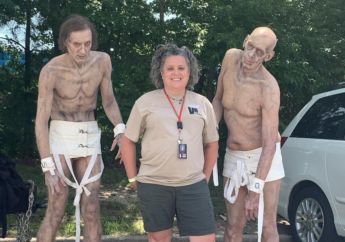 A woman standing between two men dressed as zombies 