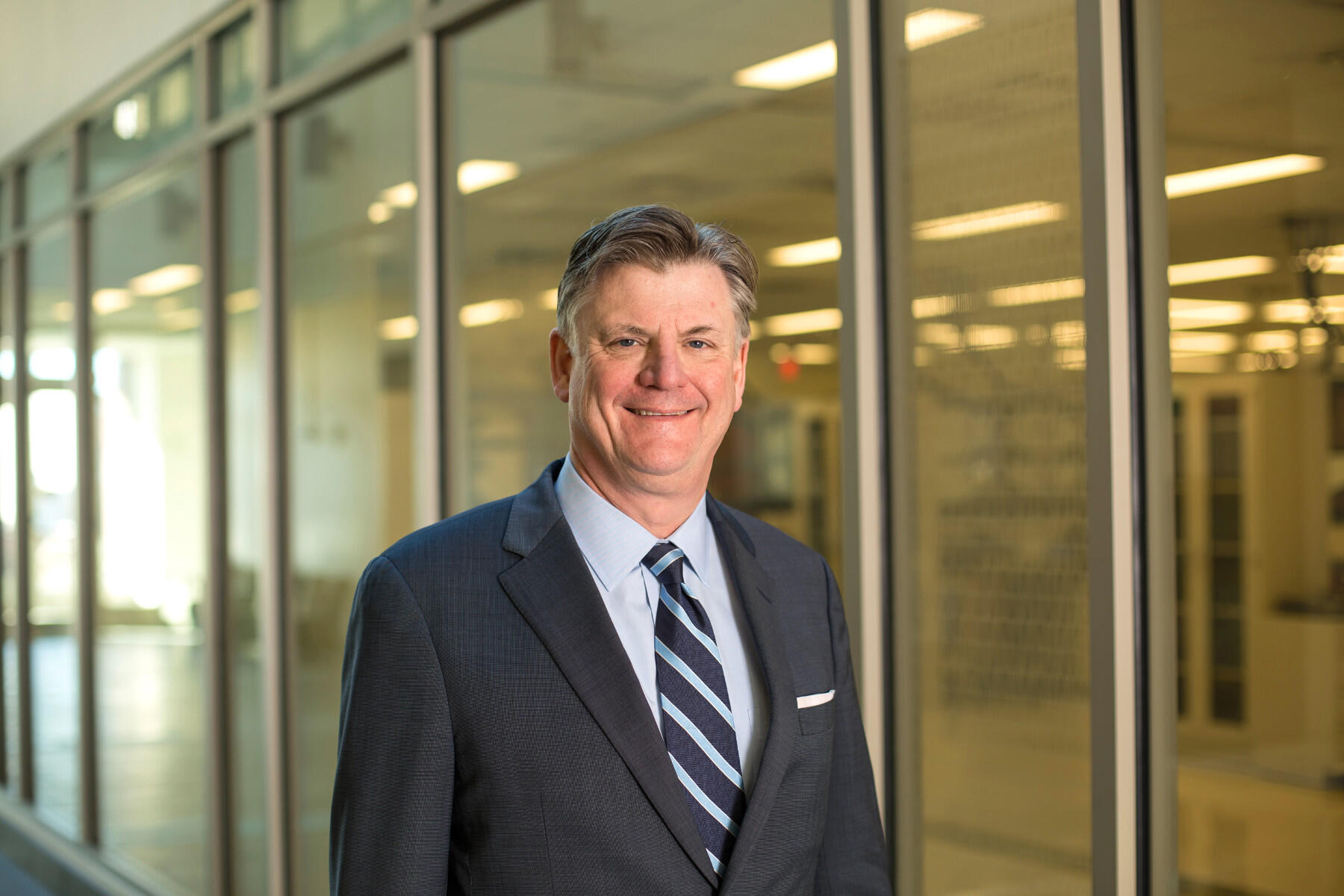 Smiling man wearing dark suit and striped blue tie.