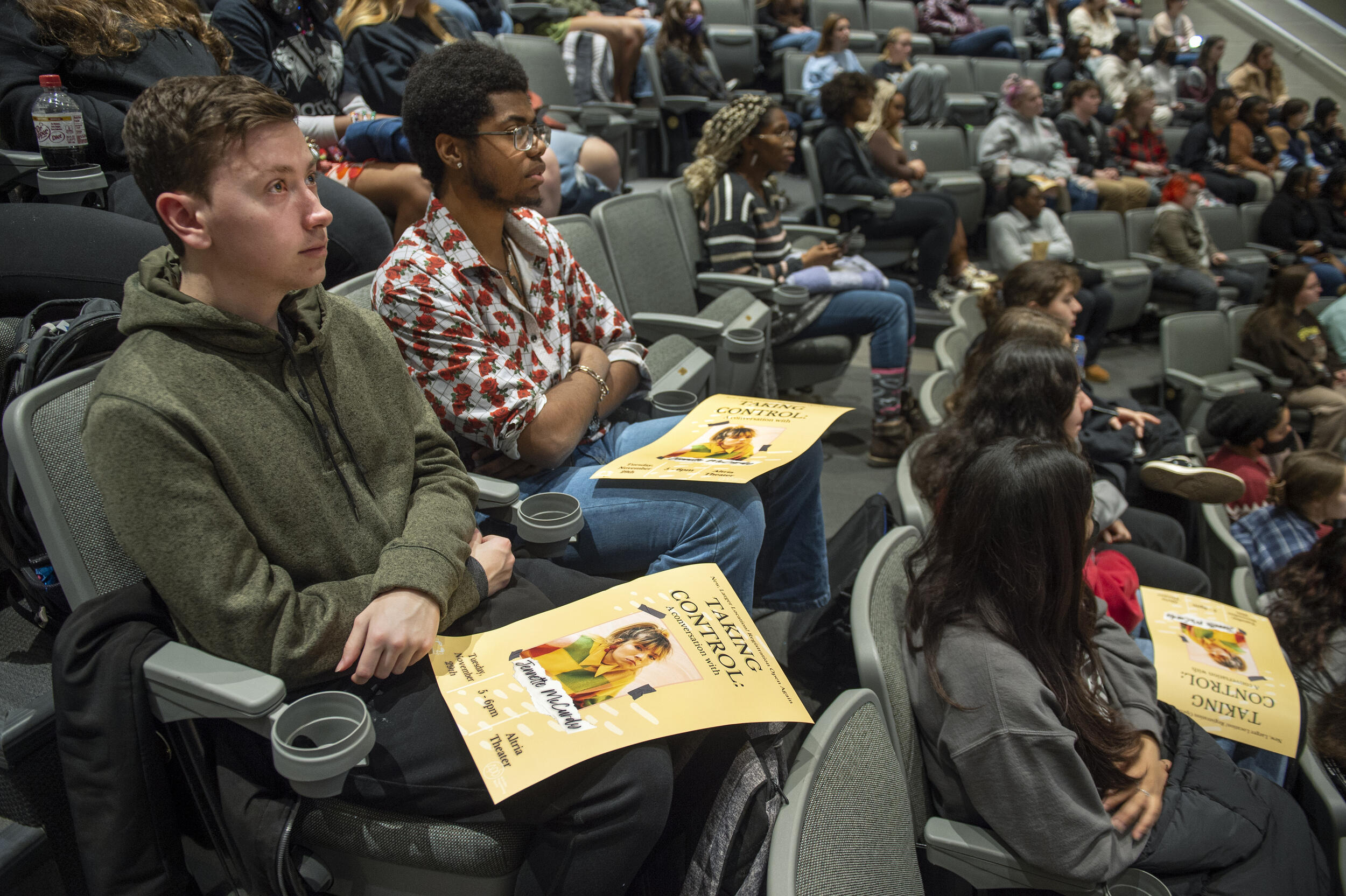 Students sitting in auditorium chairs with posters of Jenette McCurdy sitting on their laps. 