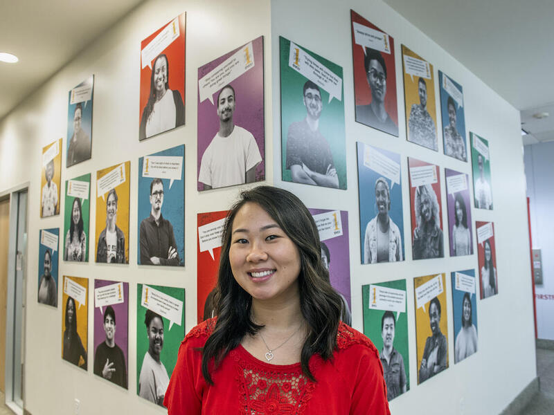 VCU student Amber Brown standing in front of a wall of portraits