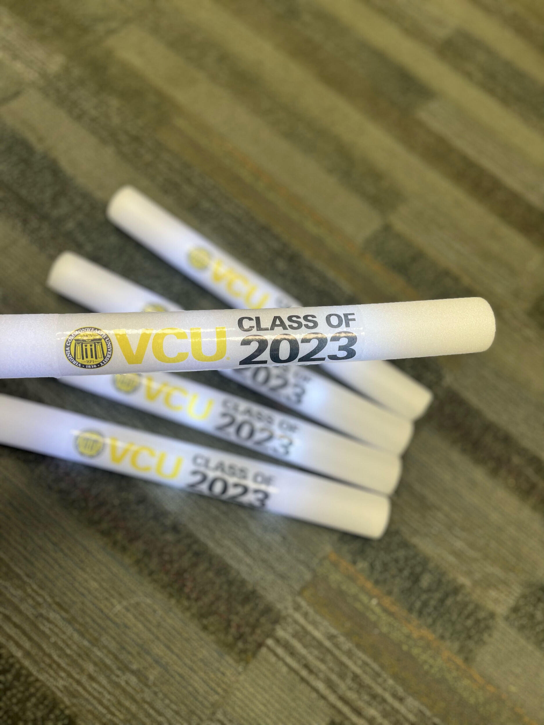 White foam sticks that say \"VCU CLASS OF 2023\" in yellow and black letters. 