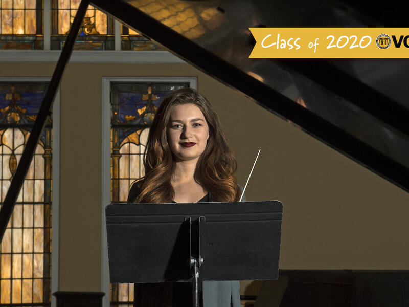 Woman stands in front of music stand.