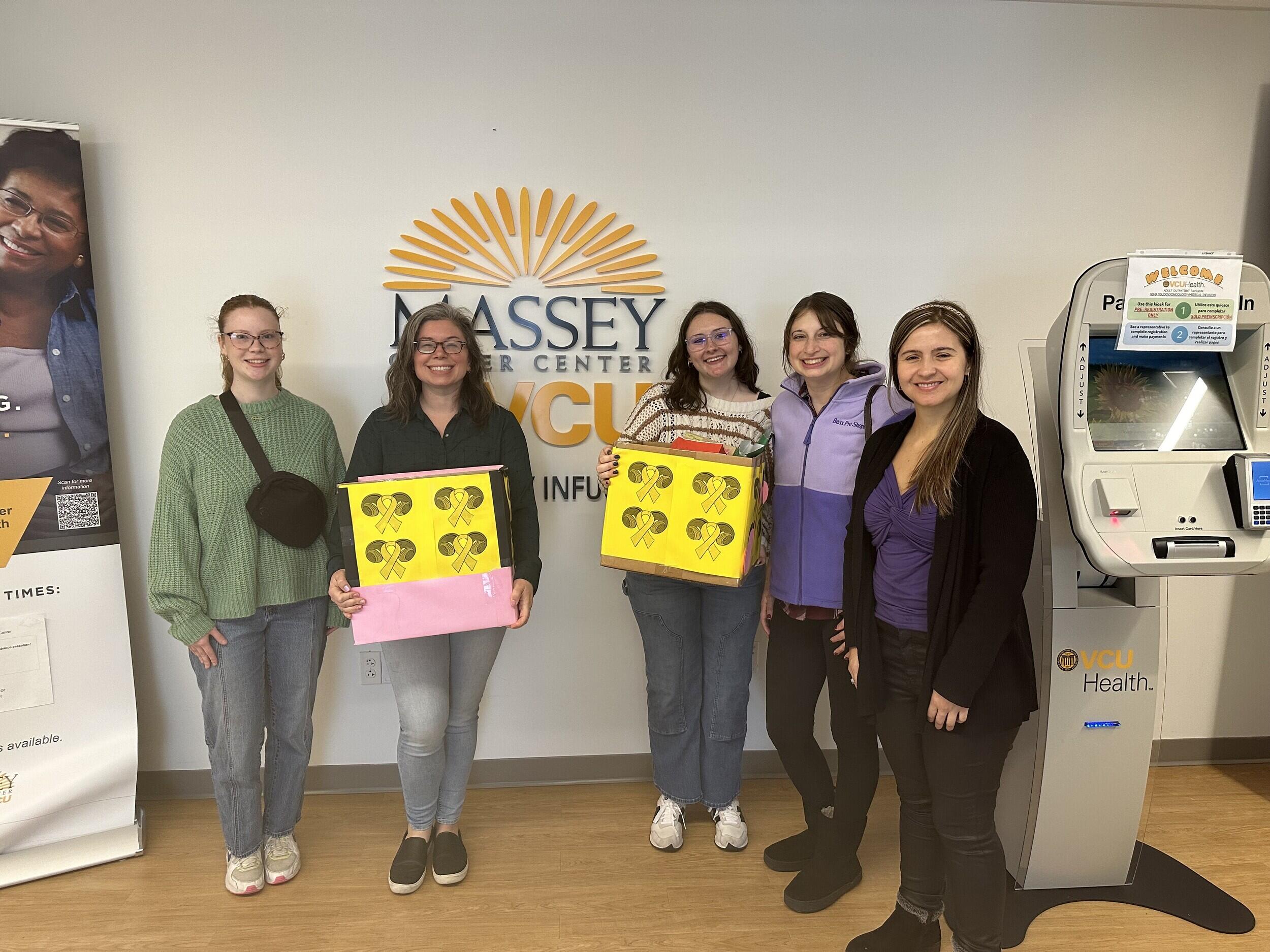 A group photo of five people standing in front of a sign that says \"MASSEY CANCER CENTER VCU\" 