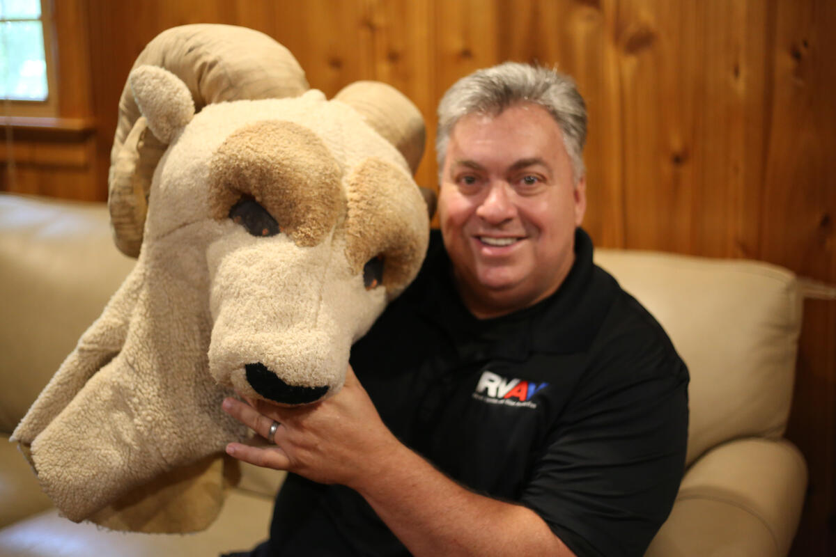 A man holding the mascot head for Rodney the Ram 