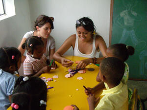 School of Social Work students Samantha Newton (center left) and Kristin Lennox (center right) are making puppets with children in a rural community school in the Dominican Republic.  Photo provided by Randi Buerlein.