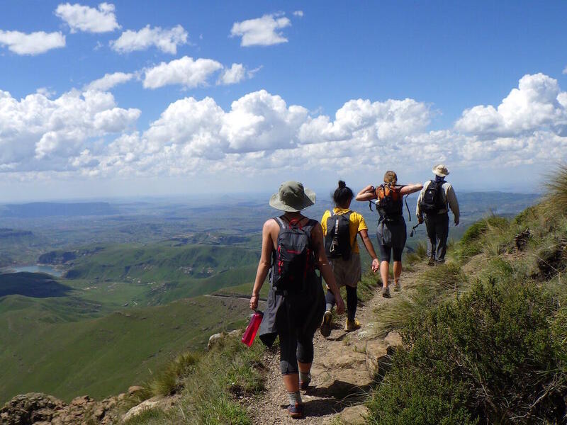 Four students hike on mountain. 