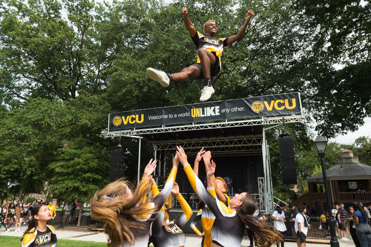 A male cheerleader being tossed into the air 