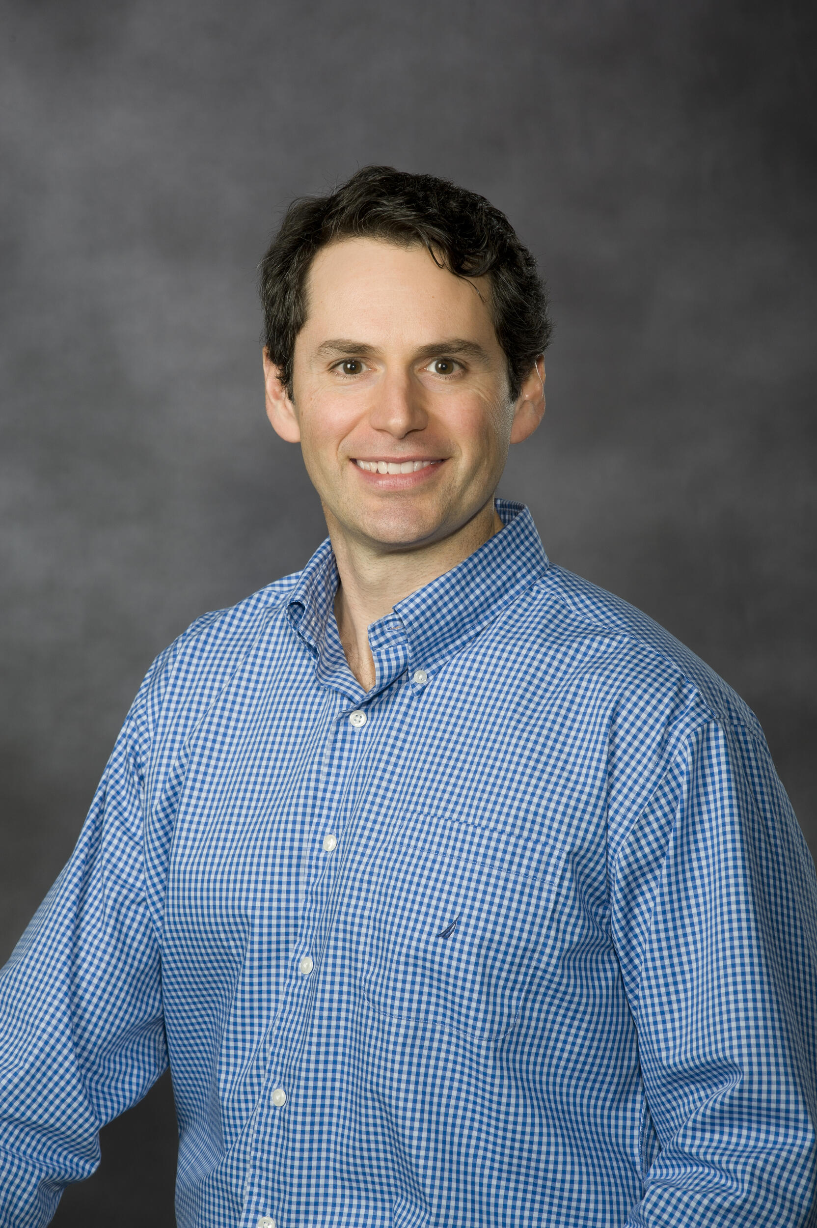 A portrait of William Pelfrey, Ph.D. smiling and wearing a blue button down shirt 