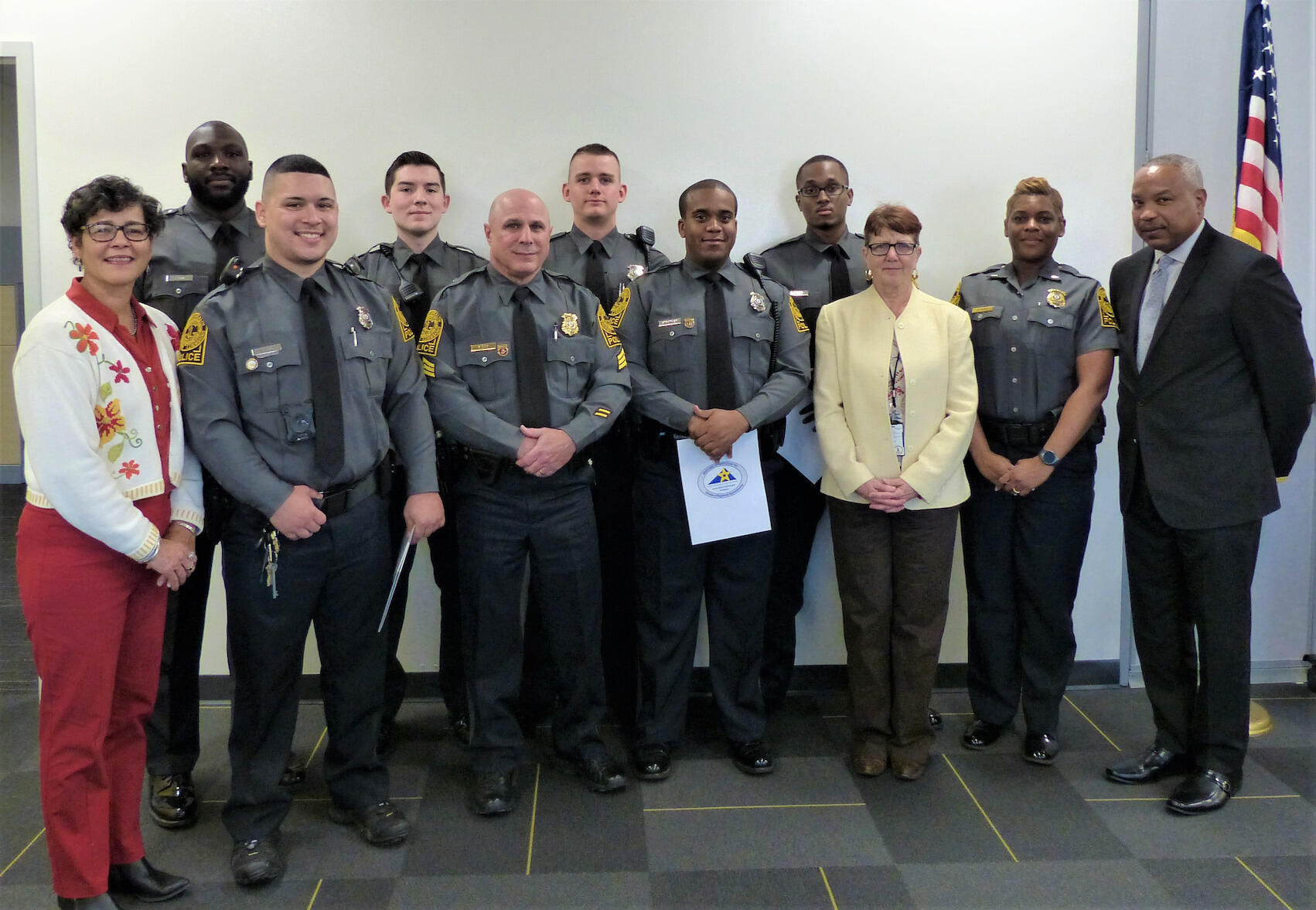 Nine people — six police officers and three non-uniformed people — pose for a photo.