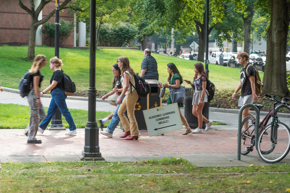 A photo of students walking across a sidewalk 