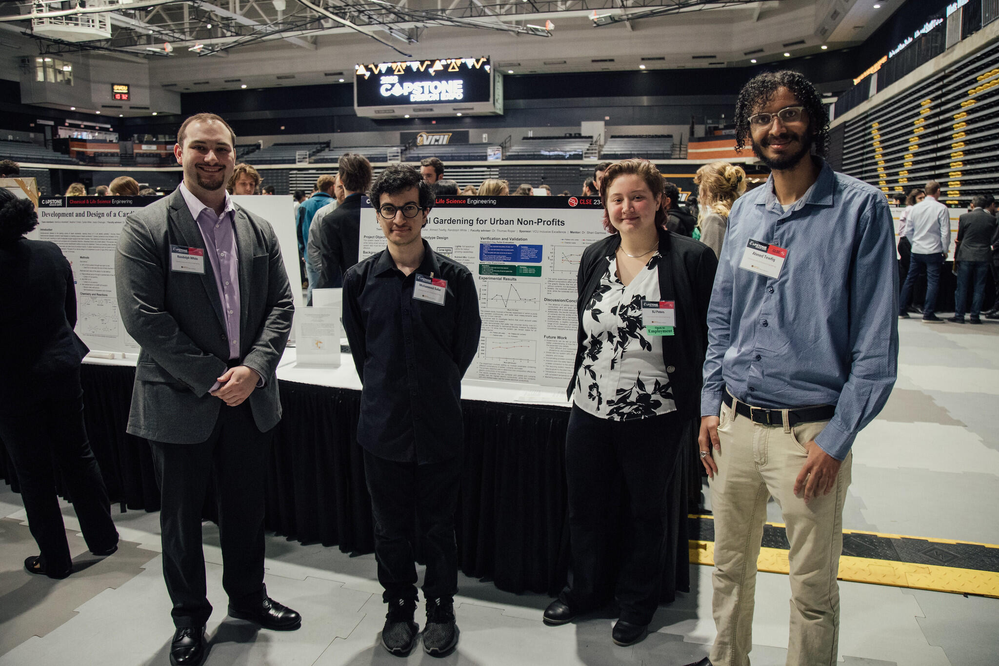 Four people standing in front of a poster board with research information on it. 