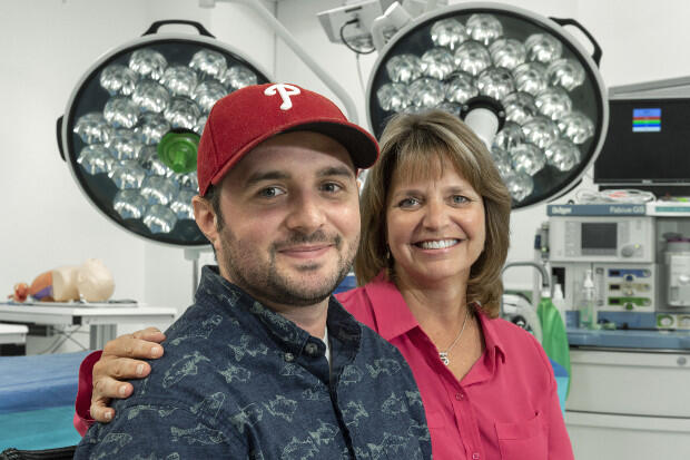 Two people, one wearing a red hat, in a hospital room.