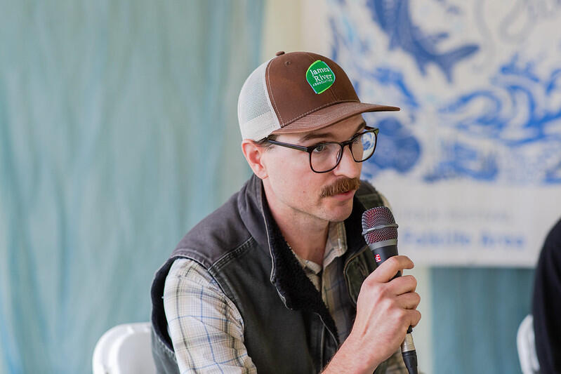 A photo of a man speaking into a microphone. 