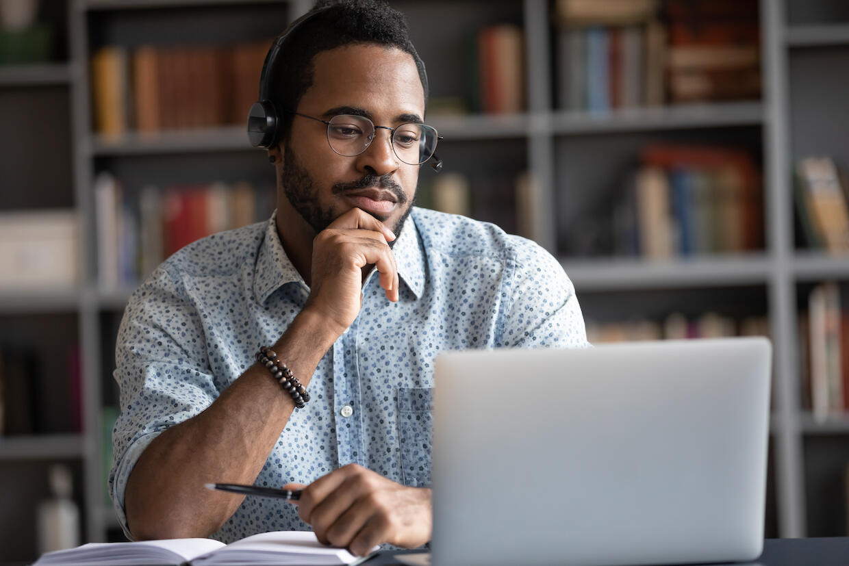 A person wearing headphones uses a laptop computer.
