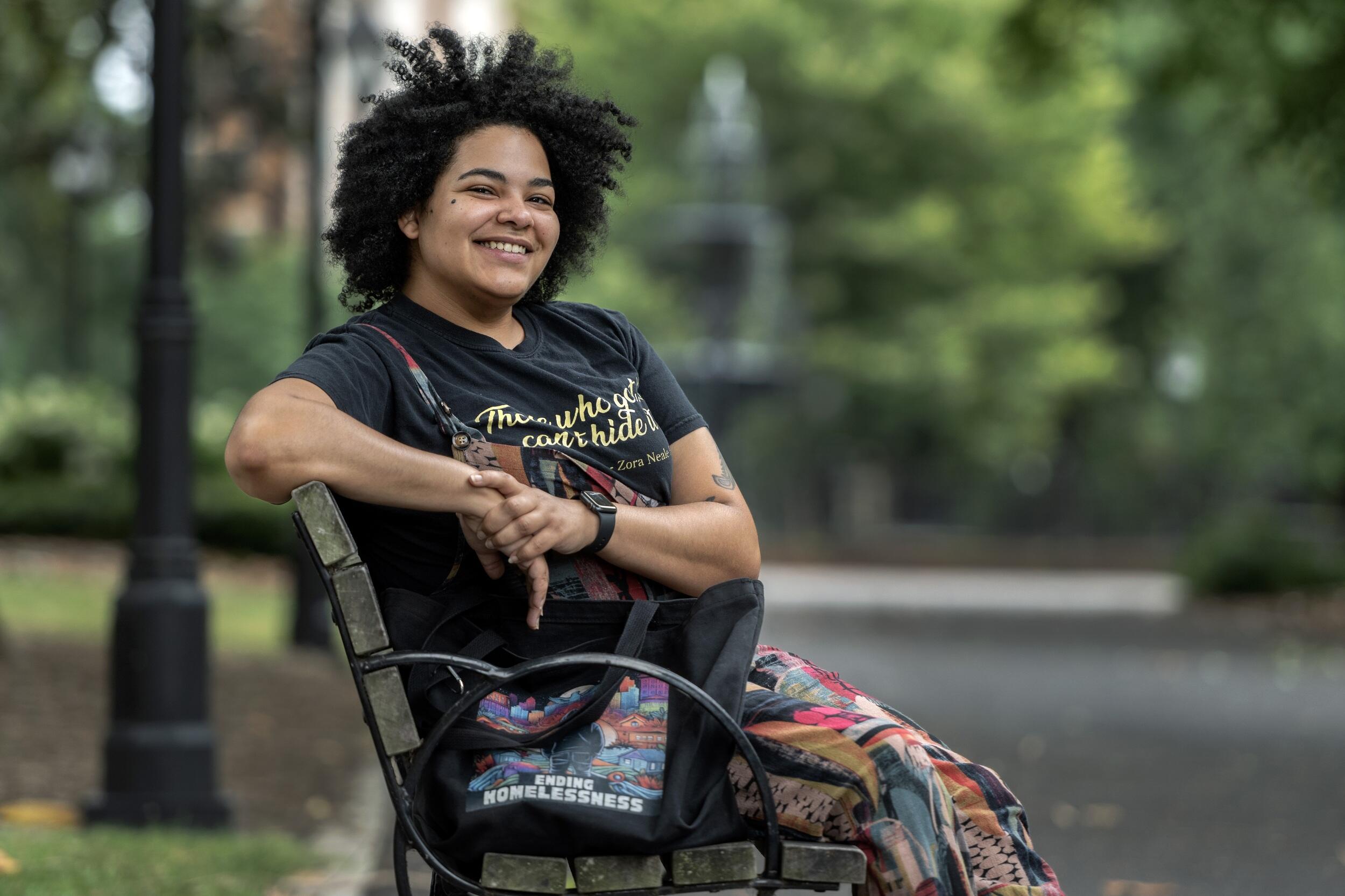 A photo of a person sitting on a bench and smiling. 
